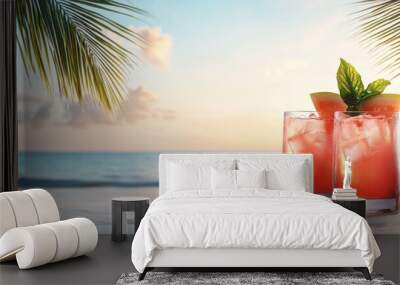 Two glasses of a red drink with a slice of watermelon on top sit on a beach Wall mural