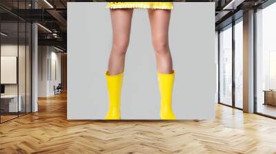 Young woman legs in Illuminating yellow dress and rubber boots on Ultimate Gray background. Colors of the 2021 year. Faceless Wall mural