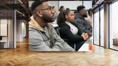 A group of people are sitting in a classroom, one of whom is wearing glasses Wall mural