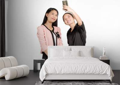 portrait of two beautiful asian business woman smiling and making a selfie with smart phone. Isolated on white background with copy space and clipping path Wall mural