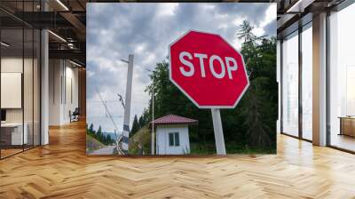 Bright red stop sign at a rural intersection with trees and clouds. Wall mural