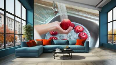 Hands of asian woman washing red apples in home kitchen sink. Wall mural