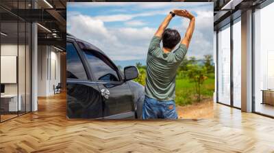 man driver is stretching after a long road trip drive to relieve her back pain. Wall mural