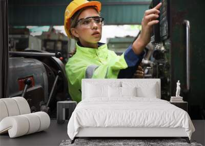 A Engineer woman using tablet or computer for inspect or checking or adjust or operate control the machine in workshop factory, the technician repair or maintenance part or equipment  Wall mural