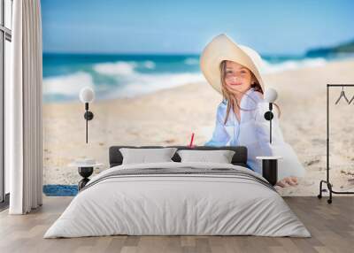 Cute little girl in a hat is resting on the beach, summer trip, vacation Wall mural