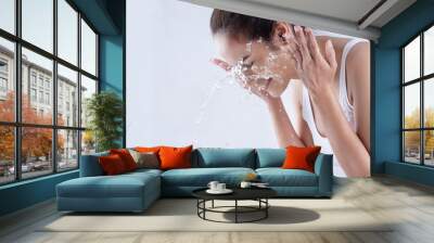 Beautiful woman washing her face in a white background studio Wall mural