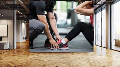 Trainer holding a woman in the leg exercise by Sid-ups. Wall mural