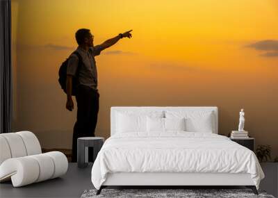 Man tourist on the cliff of the mountain on sunset background Wall mural