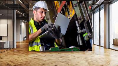 Caucasian engineer mechanic man checking for maintenance pressing metal machine by laptop at factory, worker at industrial concept Wall mural