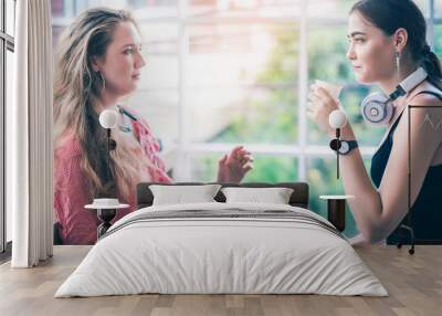 Two happy young attractive Caucasian women talking together and using smartphone or cellphone at coffee or coffe shop in the morning  Wall mural