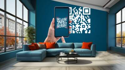 Hand using mobile smart phone scan Qr code on blue background. Cashless technology and digital money concept. Wall mural