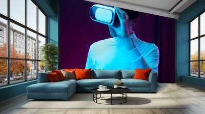 Young asian man wearing virtual reality goggles watching 360 degree video in neon light, Technology concept. Wall mural