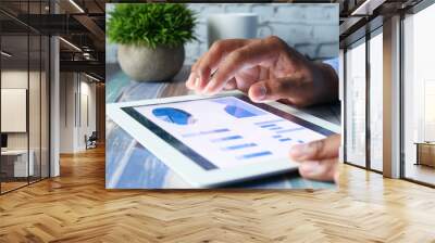 man's hand working on digital tablet at office desk, using self created chart  Wall mural