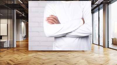 unrecognized man with casual dress arm crossed standing against white wall , Wall mural