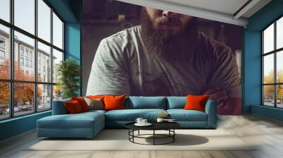 Handsome brutal man with a beard standing in his garage against the background of repair tools Wall mural