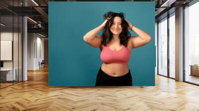 Happy plus size positive woman. Happy body positive concept. I love my body. Attractive overweight woman posing on camera in the studio on a colored background. Girl is wearing a coral bra Wall mural