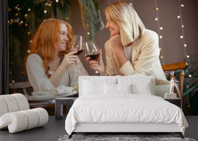 lesbian couple having dinner in a restaurant. Girls drink wine and talk Wall mural