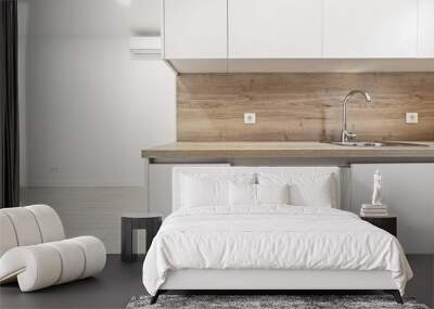 a kitchen with white cabinets and oak countertops with matching backsplashes in an empty loft style home Wall mural