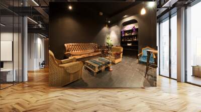 A relaxing space in a bar with armchairs upholstered in leather and vintage fabric and black walls Wall mural