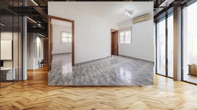 Empty room with plain white painted walls, access doors to two rooms and grayish ceramic stoneware floors Wall mural