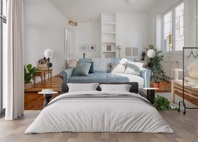 Living room with a blue three-seater sofa, wooden tables and decorative indoor plants Wall mural