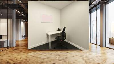 Office cubicle with small white table with telephone, black swivel chair and dark gray carpeted floors Wall mural