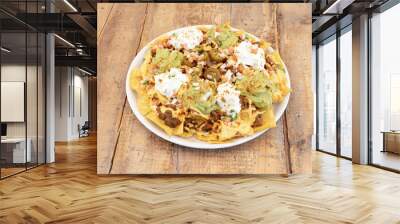 Overflowing plate of Mexican corn nachos with guacamole, cream cheese, chopped white onion, julienne tomato, chili con carne and jalapenos Wall mural