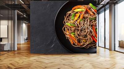 Delicious Soba Noodles with Colorful Vegetables and Sesame Seeds on Black Plate Against Dark Background Wall mural