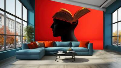 Silhouette of a Human Head with an Open Book on Top Against a Vibrant Red Background Wall mural