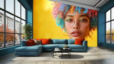 Close up portrait of young female in sunglasses with Dyed Multi Colors Hair hairstyle and brighty make-up on vibrant Yellow wall. Modern teens expressional serene outlook with individuality accent Wall mural