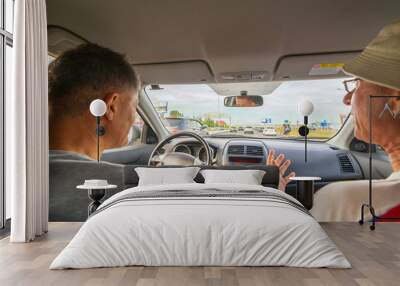 two mature men in a car driving through a city tunnel. Wall mural