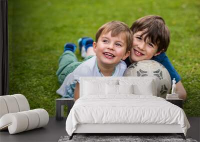 Two kids laying on the grass with a soccer ball Wall mural