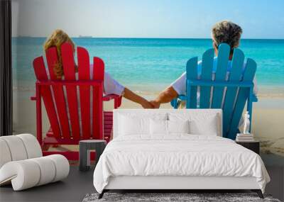 Older couple at the beach holding hands and sitting on beach chairs Wall mural