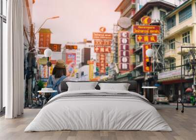 Young asian woman traveler with blue backpack and hipster hat looking map on road with tuk tuk Thailand background at China Town Bangkok. Traveling in Bangkok Thailand Wall mural