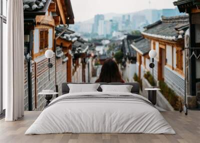 Young woman traveler traveling into Bukchon Hanok Village at Seoul city, South Korea. Bukchon Hanok Village is home to hundreds of traditional houses. Wall mural