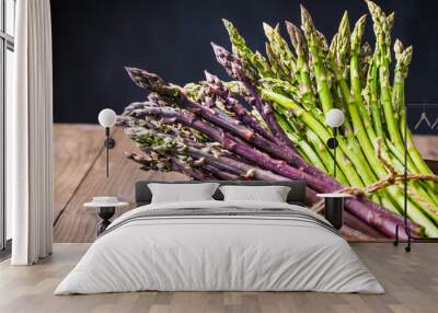 Asparagus bunches green and purple on dark wooden background. Wall mural