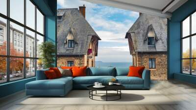 Two traditional houses in the village of Perros-Guirec, Brittany, France, with the typical sloping roof made of slate. Atlantic ocean with blue sky on the background. Wall mural