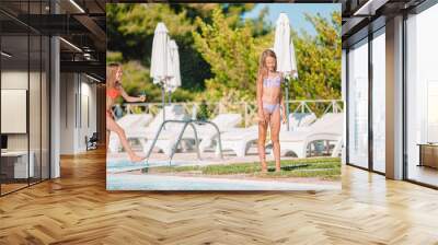 Adorable little girls playing in outdoor swimming pool on vacation Wall mural