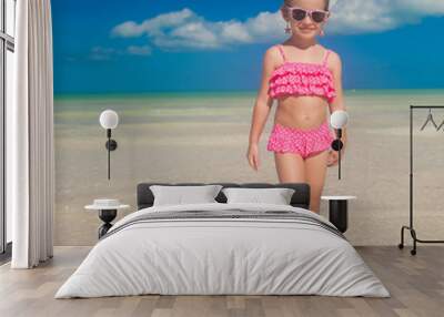 Beautiful little girl having fun on an exotic beach Wall mural