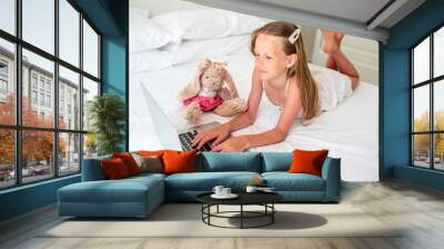 Cute little girl doing homework on laptop Wall mural