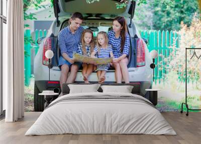 Family with two kids looking at map while traveling by car Wall mural