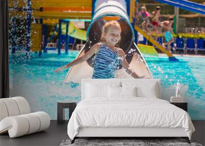 Little girl on water slide at aquapark during summer holiday Wall mural