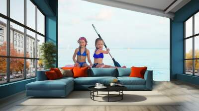 Little girls swimming on surfboard during summer vacation Wall mural