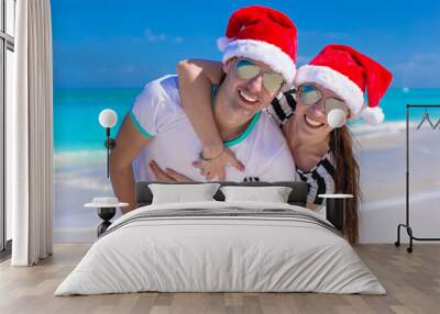 Portrait of young couple in Santa hats enjoy beach vacation Wall mural