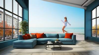 Woman on the beach enjoying summer holidays looking at the sea Wall mural