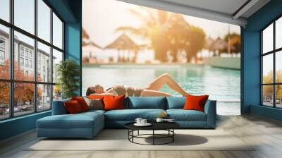 Woman relaxing by the pool in a luxury hotel resort enjoying perfect beach holiday vacation Wall mural