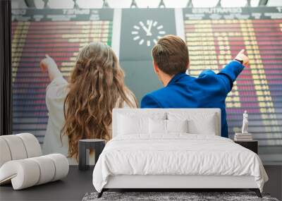 Young man and woman in international airport looking at the flight information board Wall mural