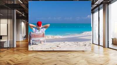 Young man in santa hat during beach vacation Wall mural