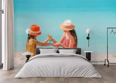 Young mother applying sun cream to daughter nose on the beach. Sun protection Wall mural