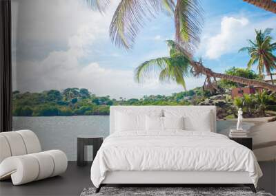 Young woman in bikini and straw hat on tropical beach. Beautiful girl under the palm tree on tropical Carlisle bay beach with white sand and turquoise ocean water at Antigua island in Caribbean Wall mural